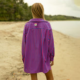 Woman wearing a pink and blue striped oversized shirt on a beach