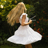 Woman twirling in a short white dress with long blonde hair.