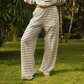 Woman wearing navy blue striped lounge pants standing on grass with greenery in the background