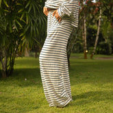 Woman wearing a long, wide-leg pants in navy blue stripes standing in a garden.