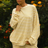 Woman wearing a yellow and white striped long-sleeve t-shirt with a blurred natural background