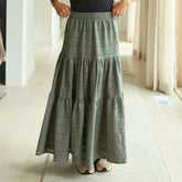 Woman wearing a long green, summery maxi skirt in a minimal indoor setting