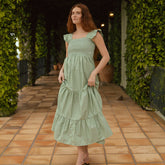 Model wearing long green dress with smocked bust and ruffle sleeves. A three tiered maxi dress with green and white stripes