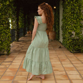 Back view of model wearing green maxi dress with three tiered skirt and ruffle sleeves