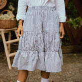 Close up of model wearing navy blue seersucker midi skirt with three tiers and an elastic waistband.