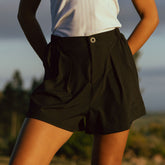 Model wearing black women's shorts with flattering pleats and made with wrinkle free material.