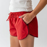 Side view of red polka dot Varsity Shorts showcasing the side pocket on a model against a light background