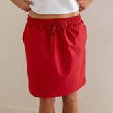 Front view of red polka dot City Skirt showcasing its drawstring and elastic waist against a neutral background