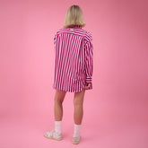 Back view of woman wearing pink and red striped matching set outfit on a pink background