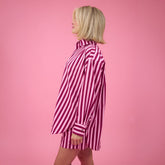 Woman wearing a pink striped button up top against a pink background