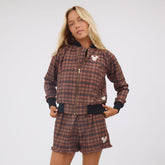 Front view of Disney Mickey Lake Shorts showcasing brown plaid fabric, Mickey patches, and ruffled hems worn by a model