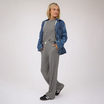 Full-length view of black stripe pajama pants on a model with a neutral studio background