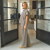 Woman in a brown striped outfit standing in a modern interior.