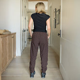 Back view of woman in a black t-shirt and brown polka dot women's joggers standing in a hallway