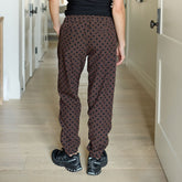 Back view of woman wearing brown and black polka dot joggers in a hallway.