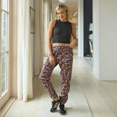 Woman wearing a black crop top and floral pants standing in a well-lit room.