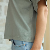 Close up of woman wearing Albion's Perfect tee in sage with a logo showing.