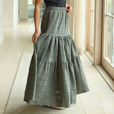Woman wearing a long women's maxi skirt in green in a bright room with large windows.