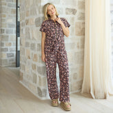 Woman wearing a floral jumpsuit standing against a stone wall.