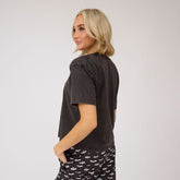 Back view of Perfect Jester Tee in vintage black with short sleeves on a model against a light background