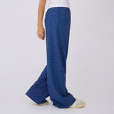 Side view of blue polka-dot slip-on trousers showcasing wide legs on a model against a light gray background