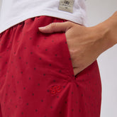 Close-up of red polka dot slip-on trouser showcasing a side pocket and embroidered Albion logo with a hand in the pocket
