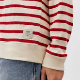 Close-up of red and cream Utah Cardigan showcasing horizontal stripes and sleeve cuff against a light background