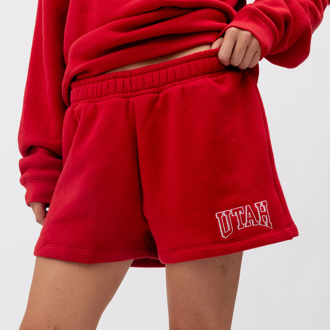 Red shorts with 'UTAH' text worn by a person on a white background