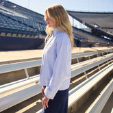 Side view of BYU Striped Collar Zip-Up Jacket showcasing light blue and white stripes on a model in stadium bleachers