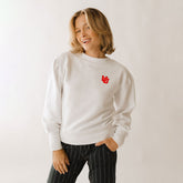 A woman smiling and wearing a white ribbed sweater with the University of Utah logo on the chest.