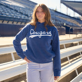 Front view of a model wearing the navy BYU Campus Hoodie with Cougars lettering in a stadium