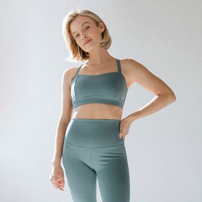 Front view of blue-grey Uplift Bra on a model, showcasing double shoulder straps and wide underband against a light gray studio background