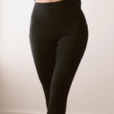 Close-up front view of black Intention Flow Capris showcasing high waist and side pocket against a light background