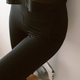 Close-up side view of black Intention Flow Capris showcasing the side pocket and high waist on a model
