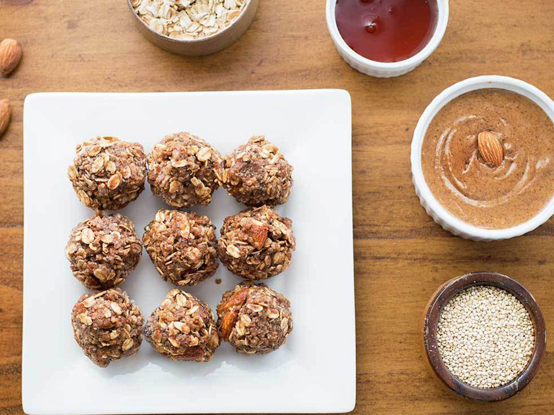 Overhead view of chocolate quinoa energy bites showcasing oats and almonds on a white plate surrounded by ingredients