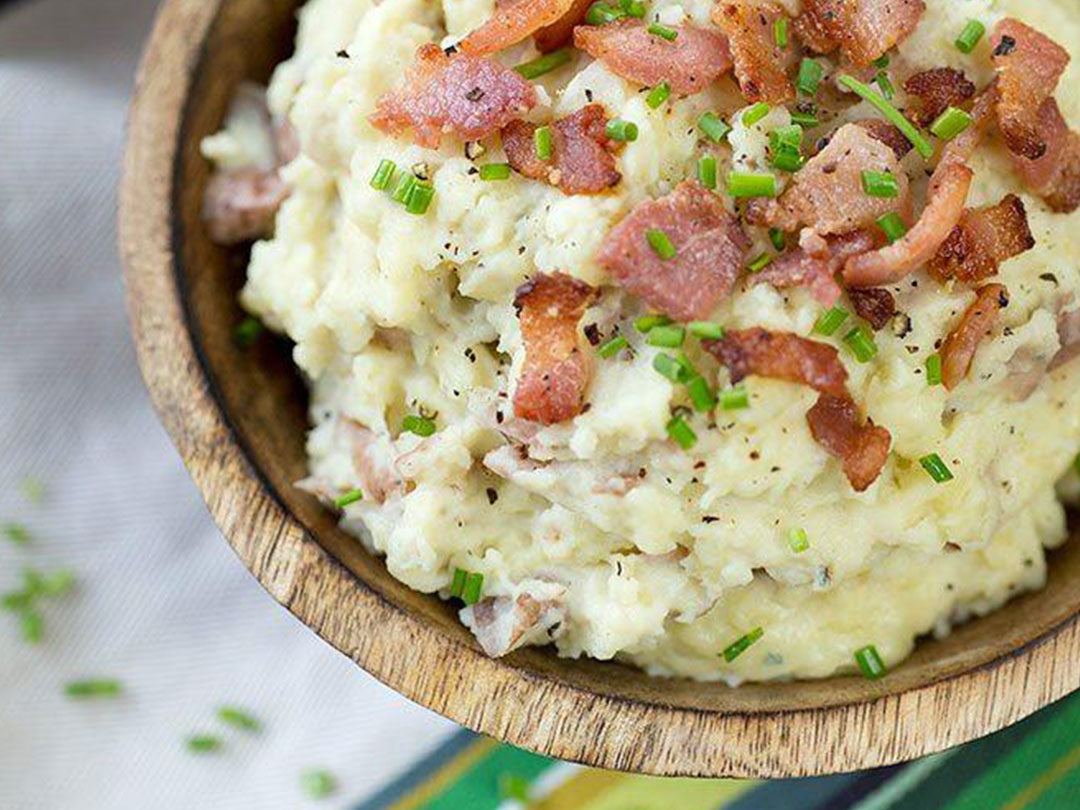 Close-up of blue cheese and bacon mashed potatoes showcasing crispy bacon and chives in a wooden bowl