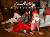 Three women lounge by a fireplace in holiday loungewear