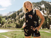 Woman posing in a black floral top and shorts in a mountain meadow