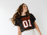 Front view of a black cropped Texas 01 football jersey showcasing mesh fabric on a model against a white background