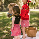 Two children standing with a small pony and wearing cute matching Disney outfits for kids.