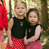 Two young girls wearing matching Disney shirts for kids with Minnie Mouse embroidery and red polka dot bottoms.