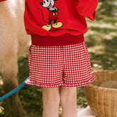 Close up back view of child wearing red gingham shorts for Disneyland. 