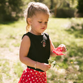 Young girl standing in a park wearing a black Minnie Mouse tank top for kids—the perfect kids Disneyland outfit. 