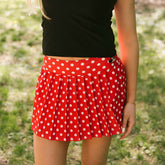 Close up of woman wearing women's Disney skirt in red polka dot print with embroidered Minnie Mouse detail. 