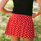 Close up back view of woman wearing a cute Disney skirt in red polka dots with blurred greenery background. 