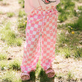 Child wearing pink checkered kid's Disney pants standing in a grassy area