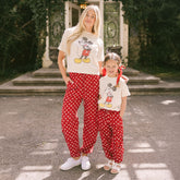 Mom and daughter wearing matching Disney outfits—cute Mickey tees and Disney pants for women and kids—standing in a courtyard. 