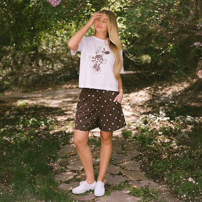 Woman standing on a stone path wearing the perfect Minnie Mouse t-shirt and subtle Disney shorts with Minnie Mouse print. 