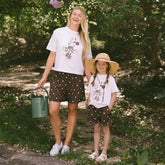 Mom and daughter standing in a garden wearing cute matching Disneyland outfits for families.