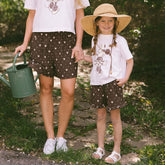 Child holding her mom's hand wearing matching Disney outfits—kids Disney t-shirt with Minnie Mouse shorts. 